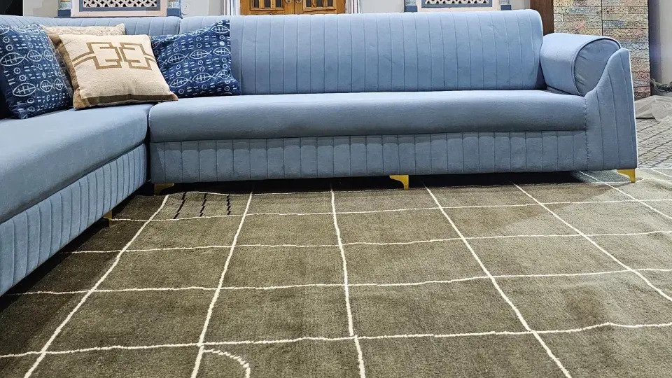 Dark grid checkered rug in a stylish living room with a blue sectional sofa and traditional decor.